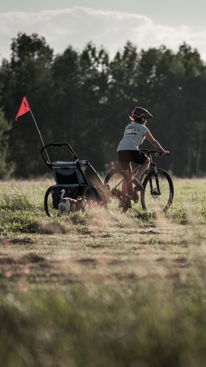 Przyczepka Thule Chariot przypięta do roweru na ścieżce rowerowej