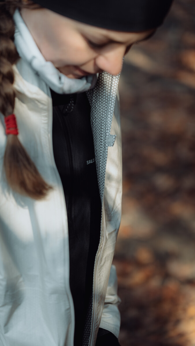 Biegaczka w odzieży Salomon SENSE AERO HYBRID pokazuje detale odzieży.