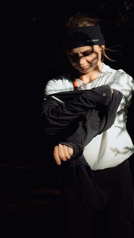 Dziewczyna w koszulce Salomon SENSE AERO GRAPHIC pokazuje warstwowe ubieranie na mróz.