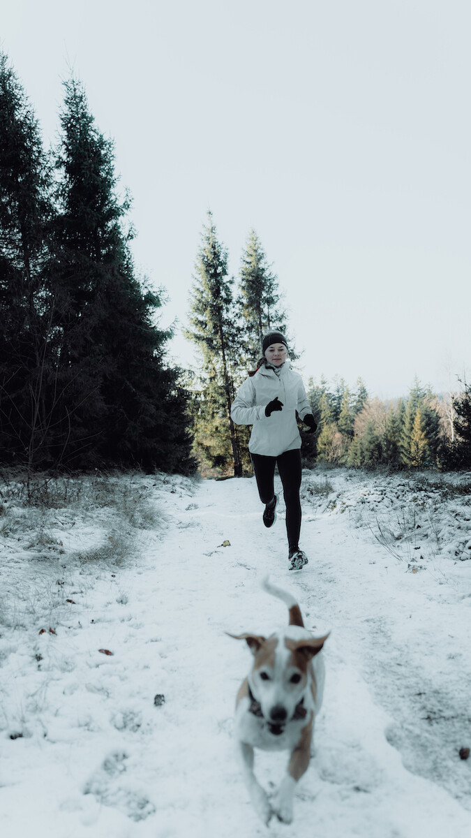 Biegaczka w odzieży Salomon SENSE AERO STOW biegnie po śniegu.