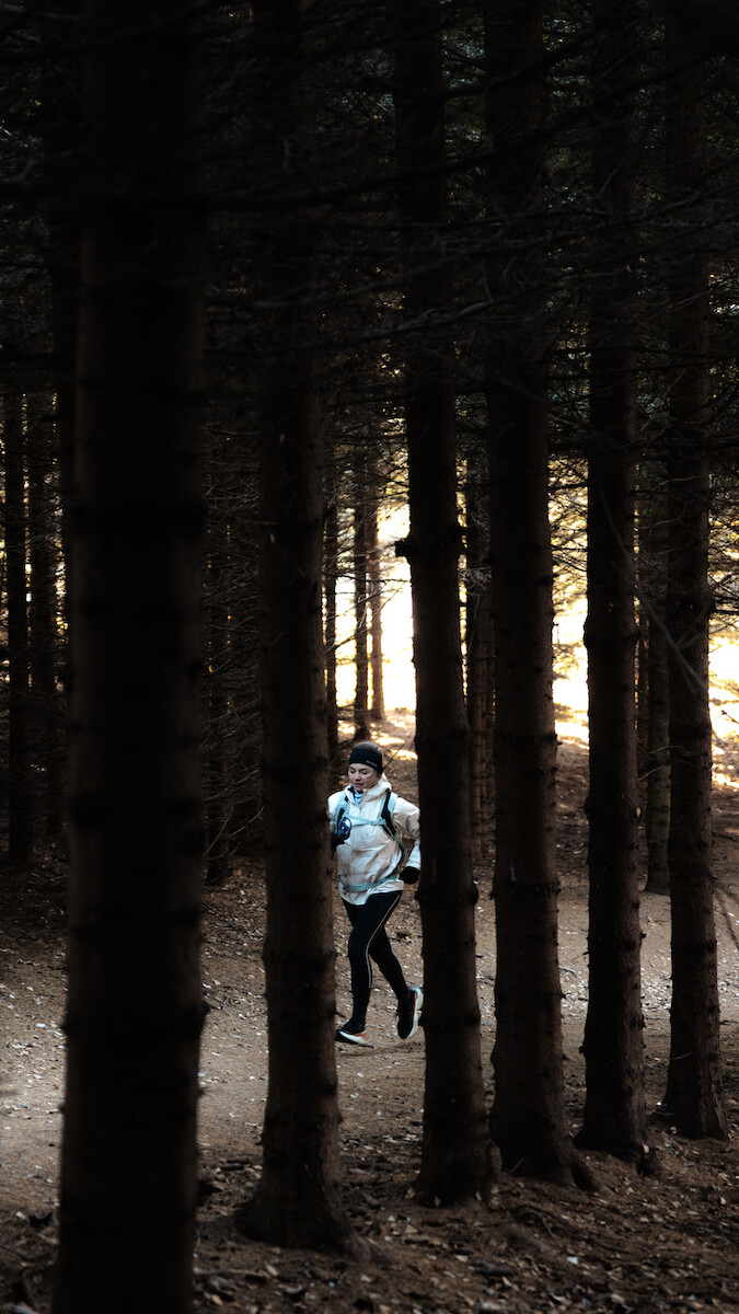 Biegaczka w odzieży i obuwiu Salomon biegnie szlakiem w Gorcach.