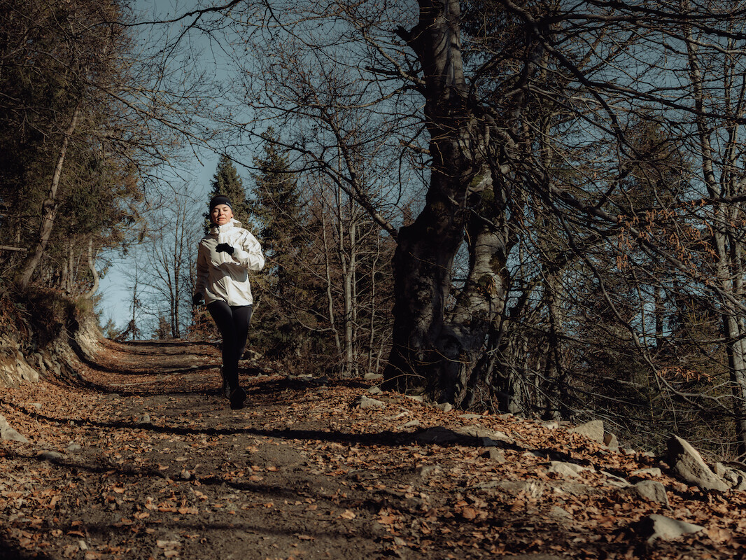 Biegaczka w odzieży i obuwiu Salomon biegnie szlakiem w Gorcach.